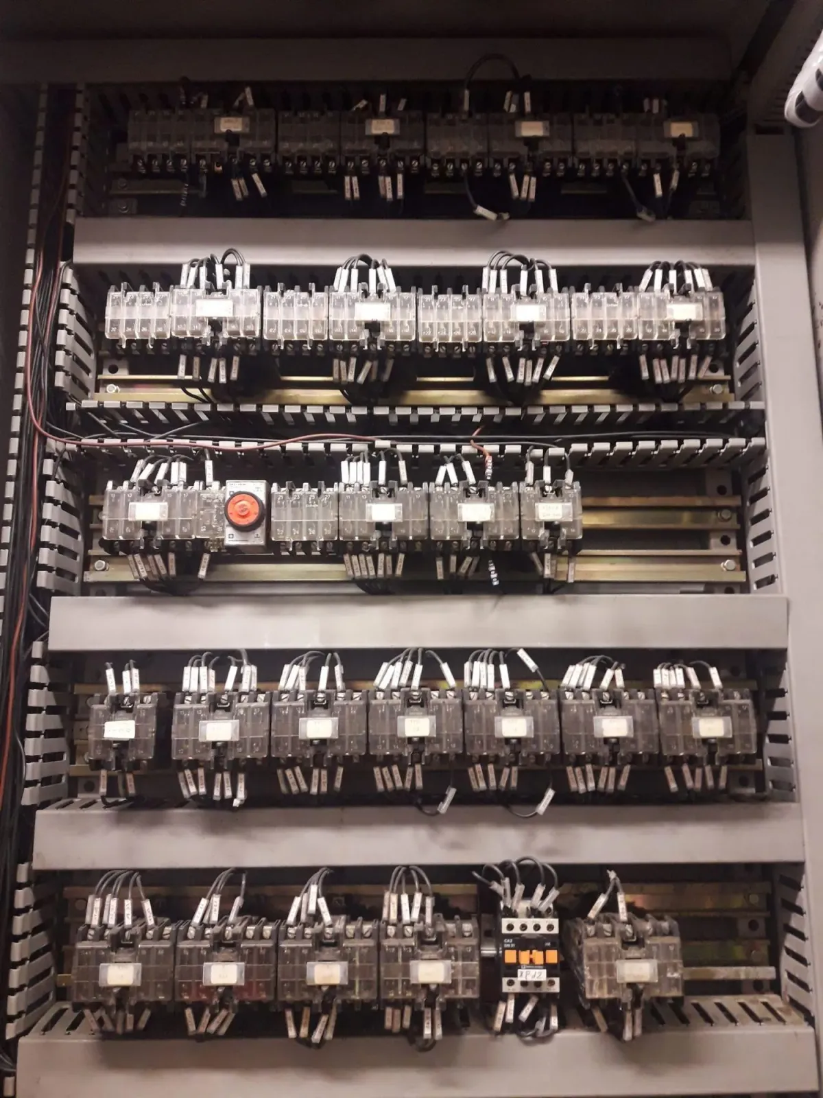 Electrical cabinet with several rows of labelled relays and terminal blocks